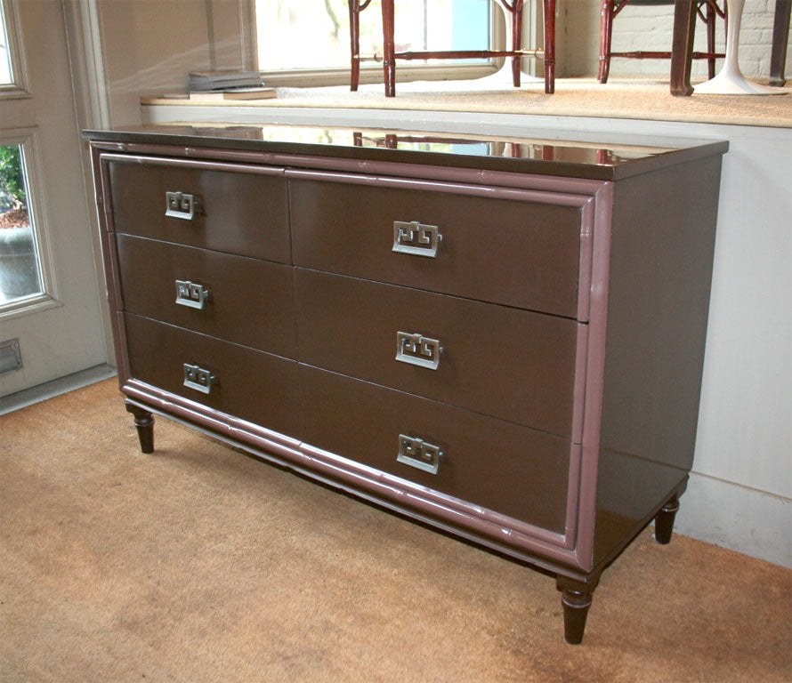 Brown lacquered chest of drawers with decorative bamboo trim

and Asian inspired hardware.