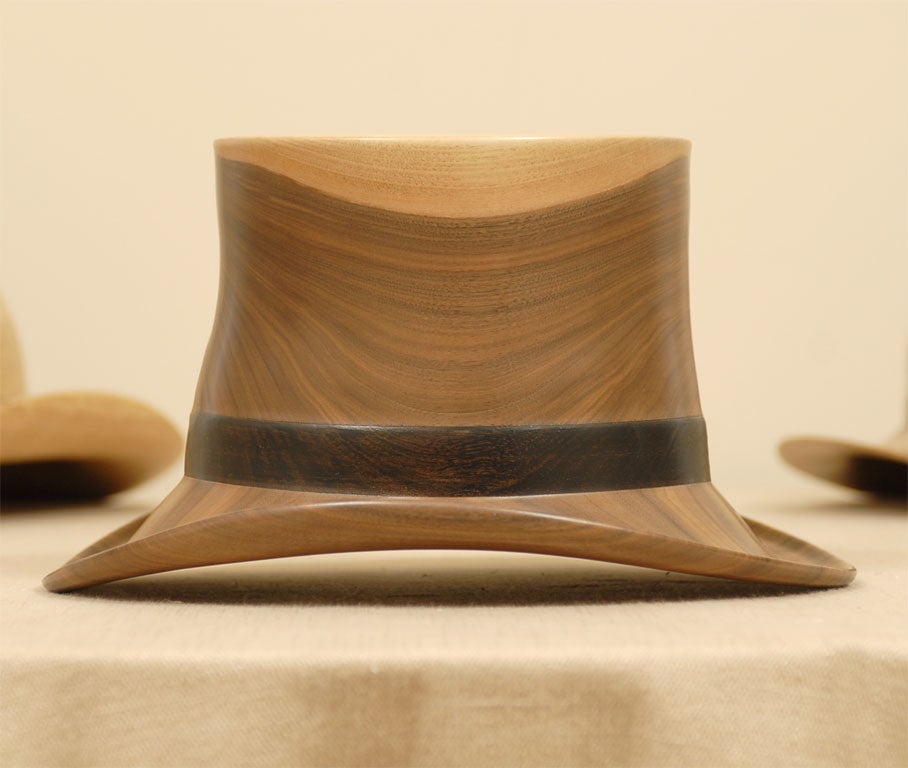 An incredible set of three hats, all of turned wood by American artist, Chris Ramsey.  Two are Western influenced, and one is a top hat.  All are signed, numbered, and dated.  The largest is signed 