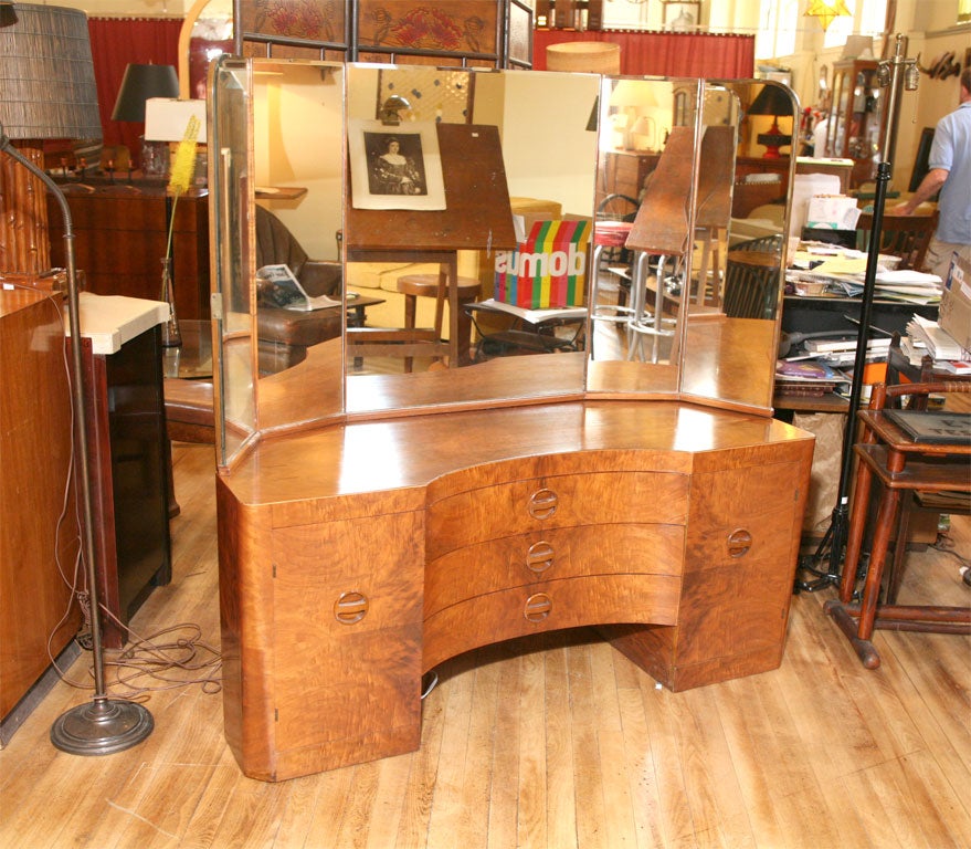 Vanity, with beautiful bookmatched veneers, and diminutive inset pulls.  Five indivual pieces of glass create a wraparound viewing ability. Two cabinets flank three central drawers. Includes wonderful, original matching swivel chair. (chair not