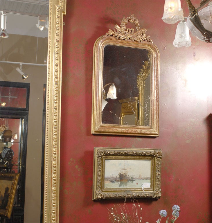 19th Century Louis Philippe Mirror with red gesso showing through on frame, original glass, and carved wreath and torcheres at crown.