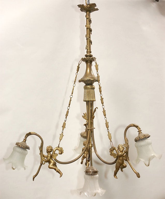 This classic chandelier is elegantly pleasing to the eye. Simple in its design with three cherubic figures supporting floral stems as three shaded down lights. A fourth central light completes the ensemble. Decorative elements include: a central