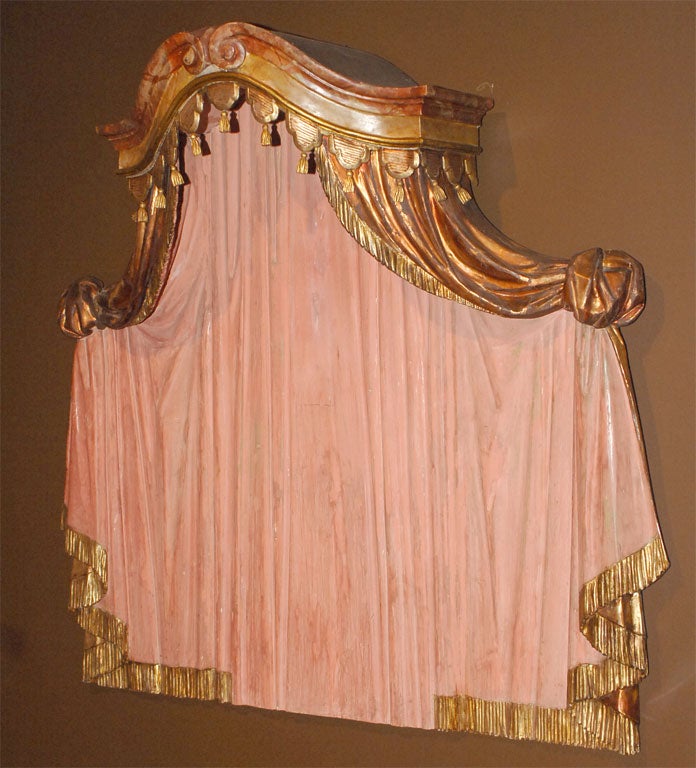 the overhanging central cartouche<br />
with faux marble carved wood gentle scroll<br />
surmounted by carved wood parcel gilt tassels<br />
the drapery panels having pulled effect<br />
with tied corners draping down to <br />
parcel gilt