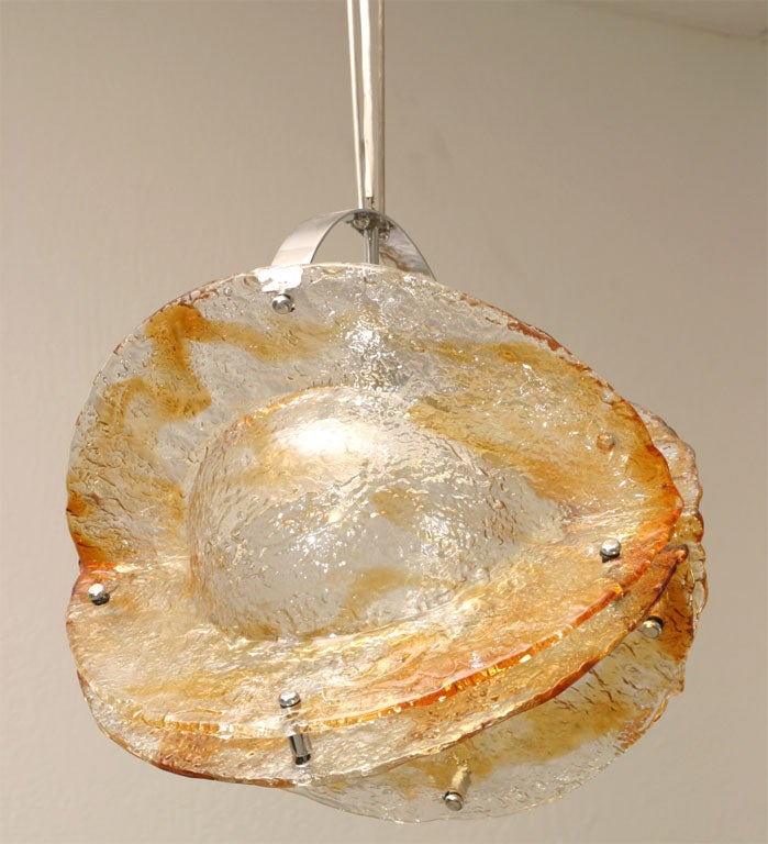 This Mazzega light fixture is a sculptural work of art. In terms of imagery it looks like a planet ablaze. It is substantial and impressive with colors ranging from orange to clear.