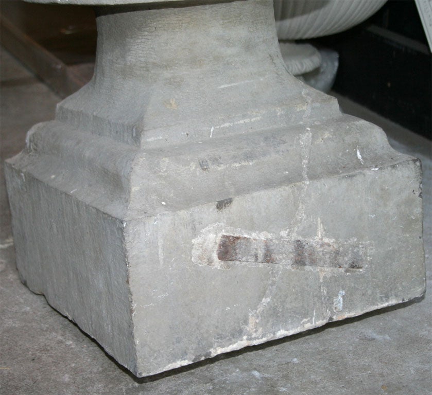 A pair of highly stylized carved stone pineapple pier finials, rainsed on a square stepped bass.