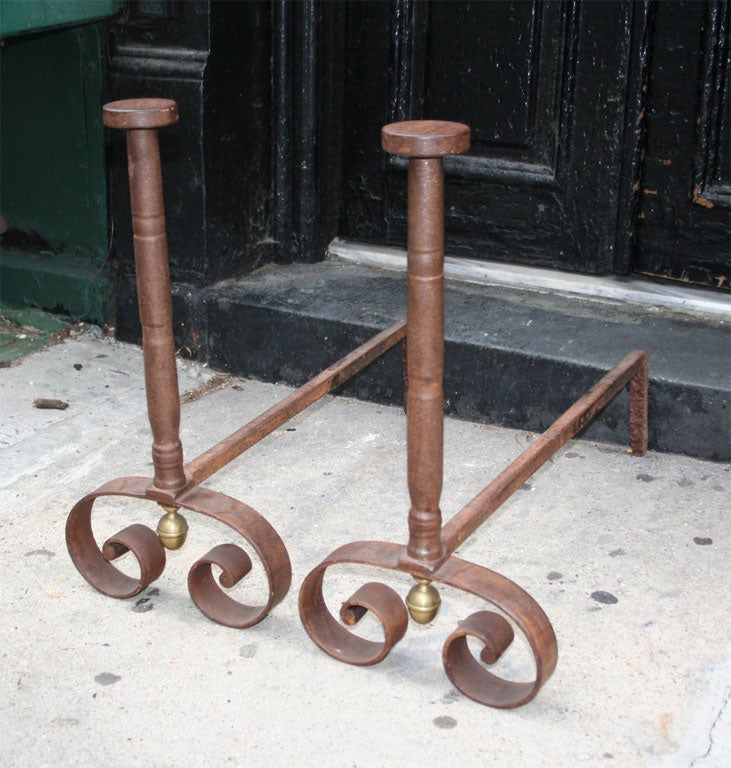 A pair of boldly executed French 19th century steel andirons having nail-head tops on ring turned shafts standing on scrolled legs with decorative brass egg drop finials.  Very graphic form.