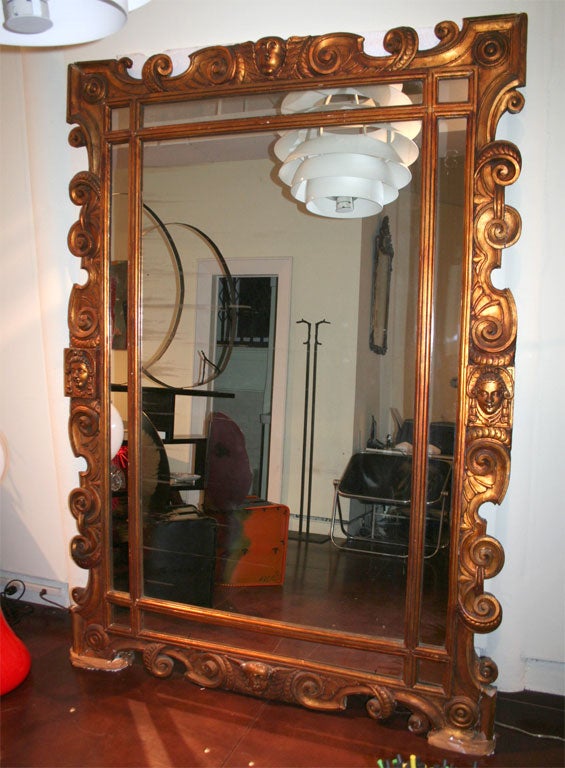 Very large mirror with an unusual bronze leaf finish. Four faces decorate this impressive mirror.