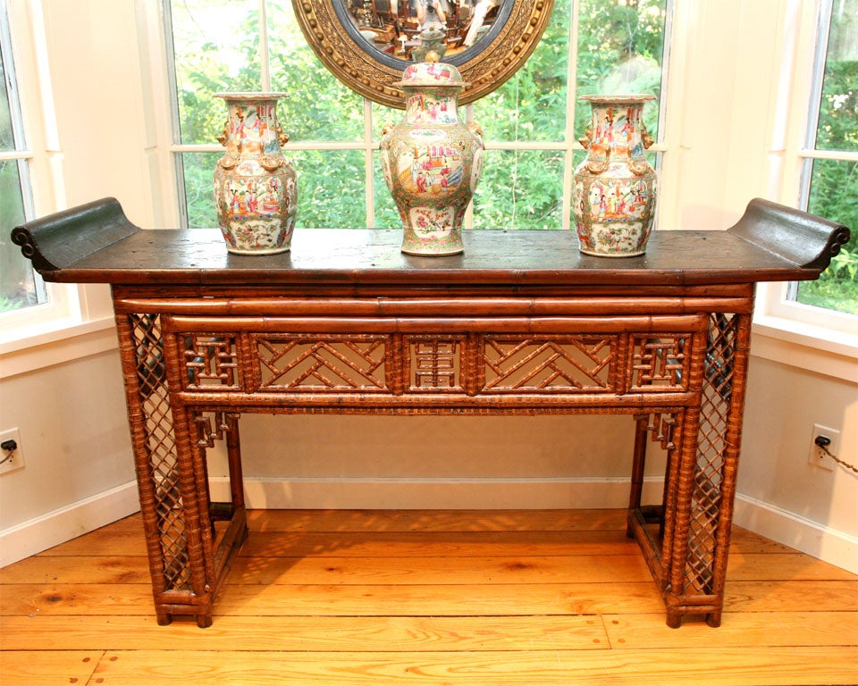 This unusual freestanding bamboo altar table has a black lacquer elm top with everted ends above a frieze and sides of latticework.  The back has a different latticework pattern from the front. From the Henan Province in northern China.