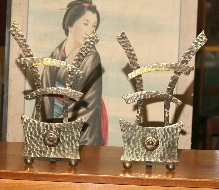 A pair of hand-hammered brass andirons in the form of a Chinese character.  Solid brass with iron backs.