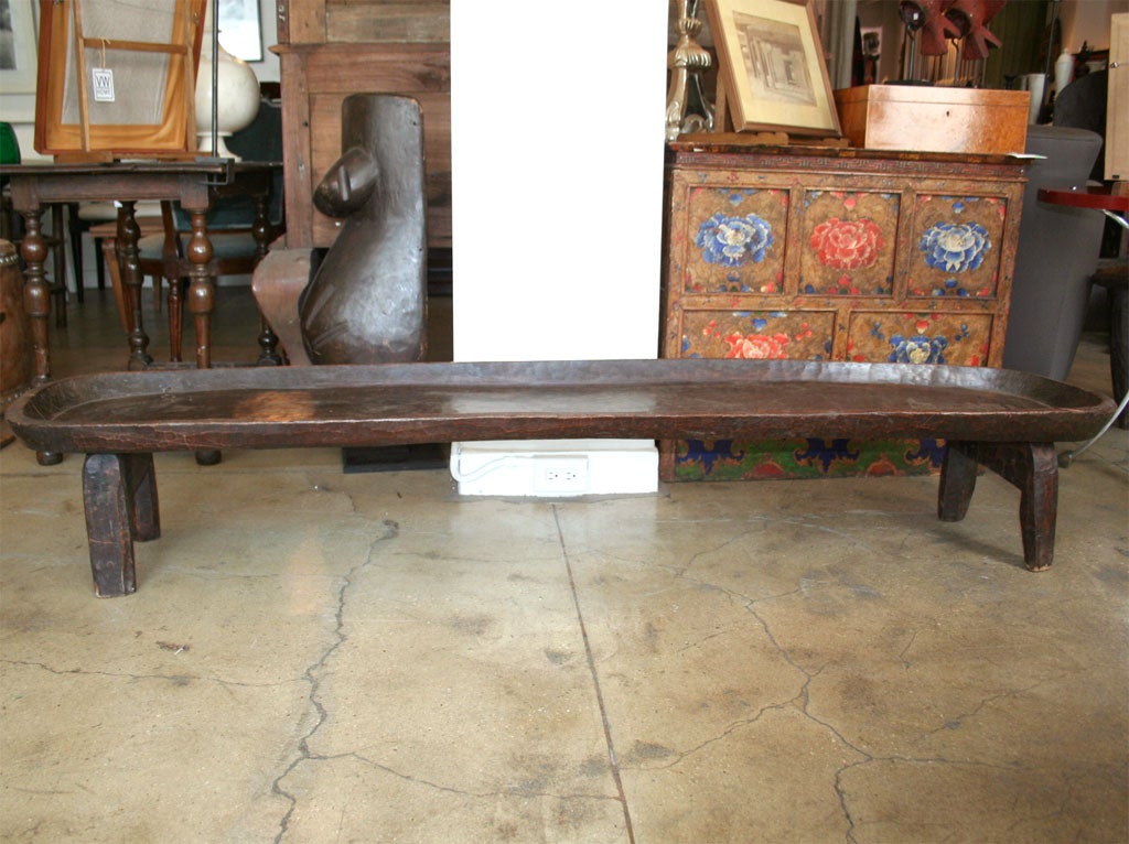 A hand-carved long wooden bed.  Useful as a low serving table, coffee table, or long pedestal stand.
