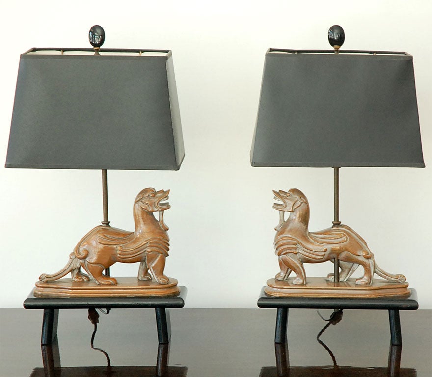 Small pair of carved wood Foo Dog lamps on black painted bases with black paper shades.