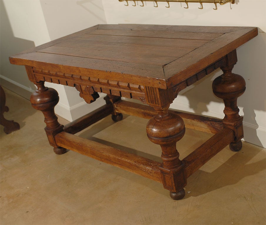 A French fruitwood table from the 19th century, with planked top, carved apron and bulbous legs. Created in France during the 19th century, this table features a rectangular planked top sitting above an eye-catching apron, adorned in its center with
