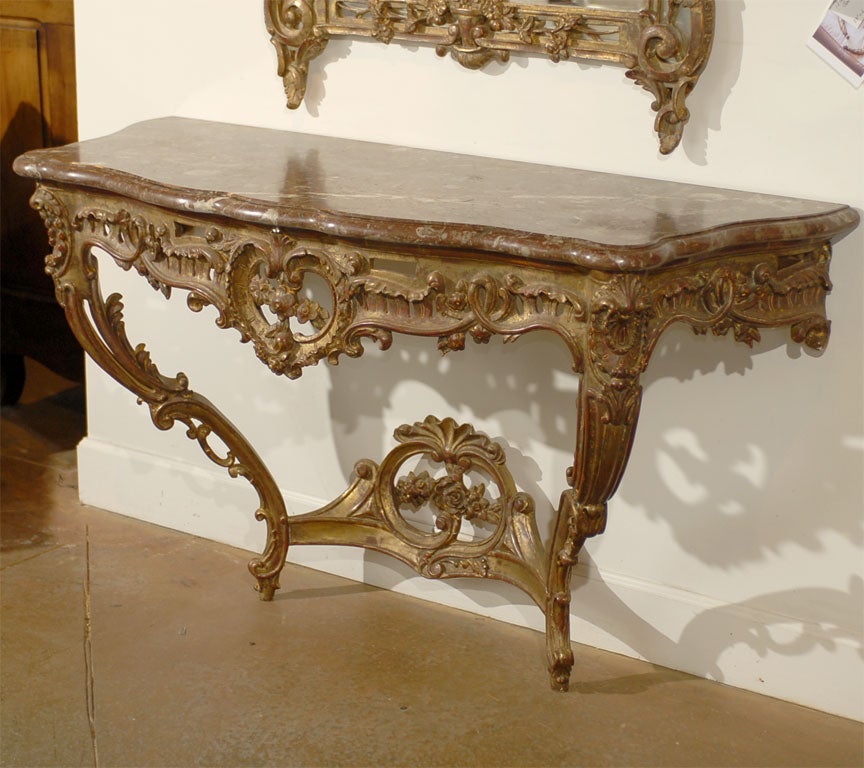 A French Rococo style carved giltwood console table from the late 19th century, with red marble top. Born in France during the last decade of the 19th century, this console table features a variegated red marble top with serpentine silhouette,