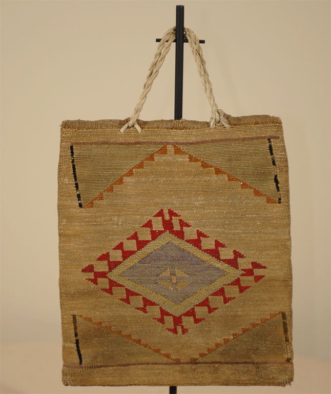 A beautifully woven bag of corn husks with different polychrome geometric designs on each side.  The bag is in excellent condition, and the decoration still has nice color retention.  The rope handles are a replacement or later addition.