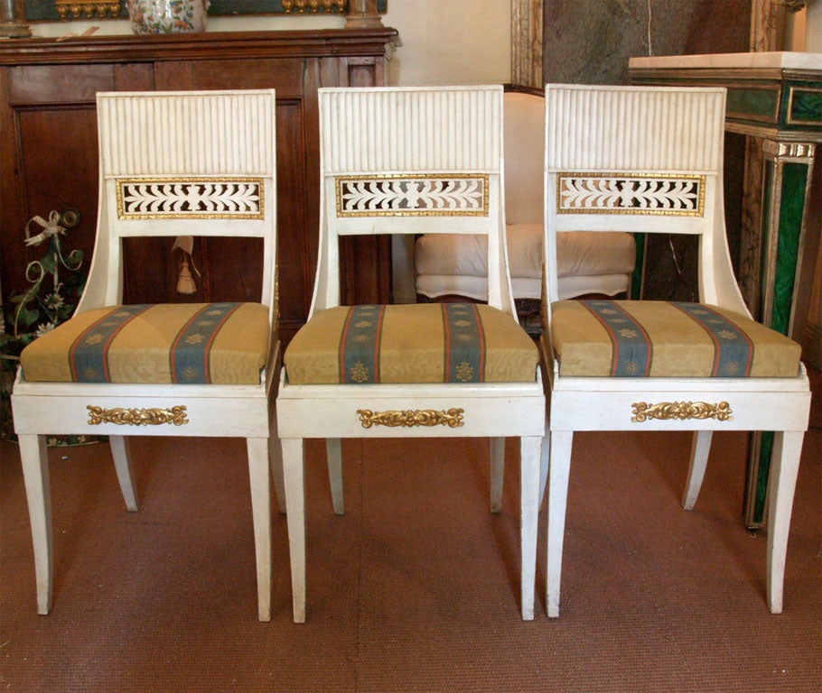 Consulate style painted dining chairs with separate cushion. Backs are fluted and pierced with gilded frame