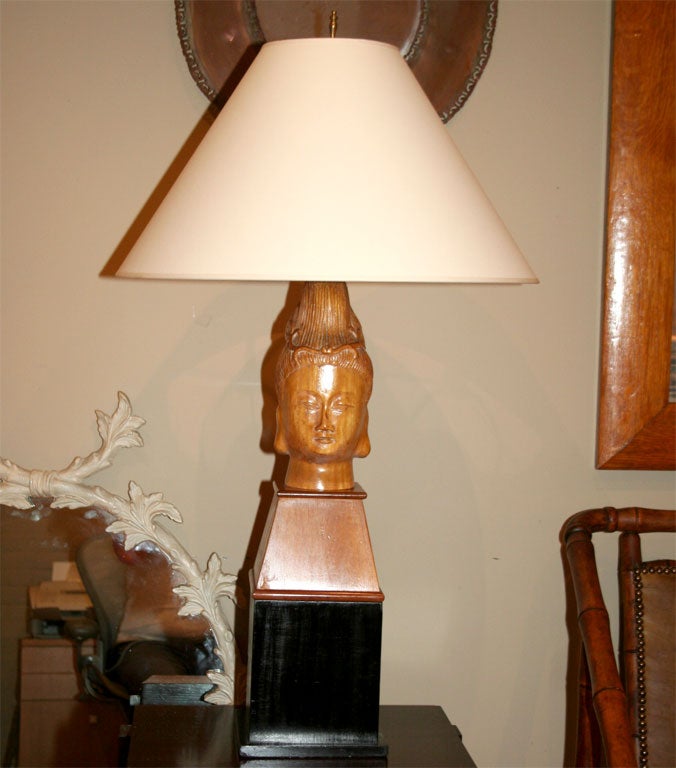 Pair of carved wooden lamps in the form of an Asian Goddess sitting on large black bases. In the style of James Mont.