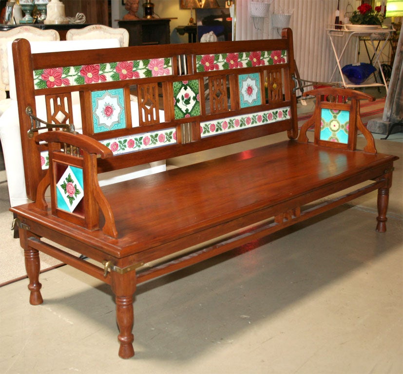 Colonial bench inset with floral and stylized tiles on front and reverse of hinged back that swings forward to change seat direction.