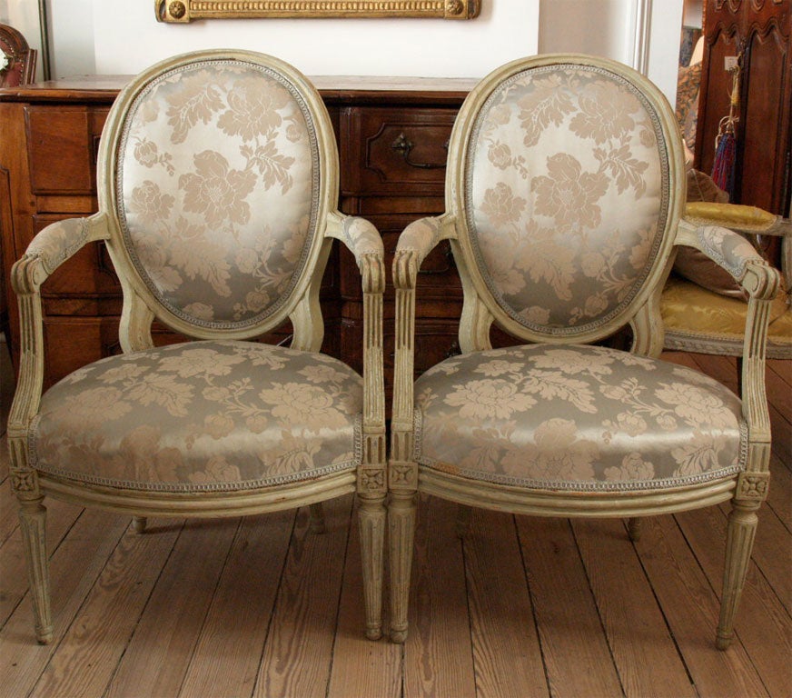 Painted pale gray fauteuils with fluted legs and oval backs.