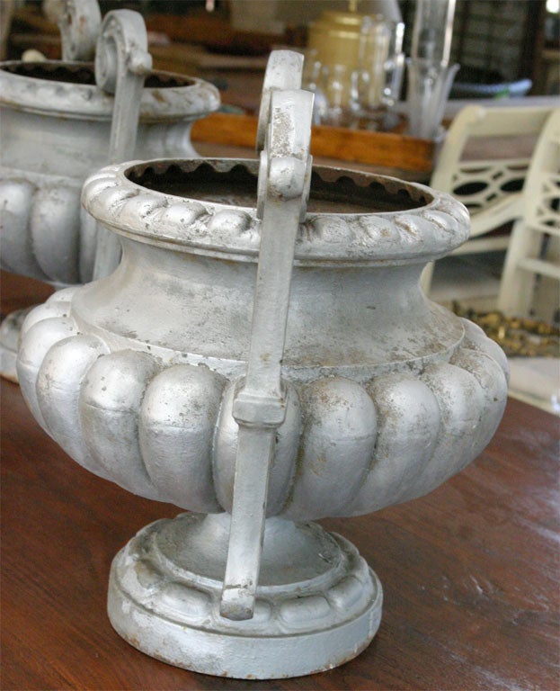 Pair of double handled melon bulbous shaped urns topped with a large lip. The French classical style cast iron garden urn has a plaque with 'CORNEAU ALFRED A CHARLEVILLE' foundry stamp, one of the manufacturers of art castings of the second half of