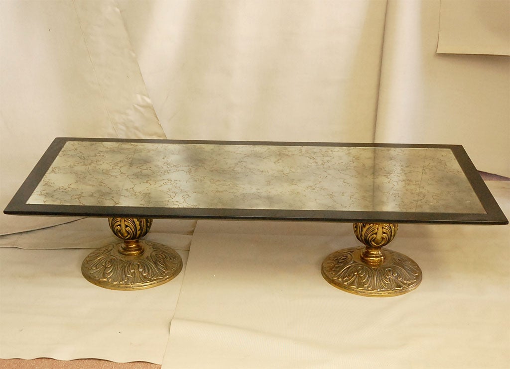 BEAUTIFUL MOLDED BRASS BASE TABLE. TOP IS ANTIQUED MIRROR WITH GOLD DETAILS. BORDERS ARE EBONIZED WOOD.
