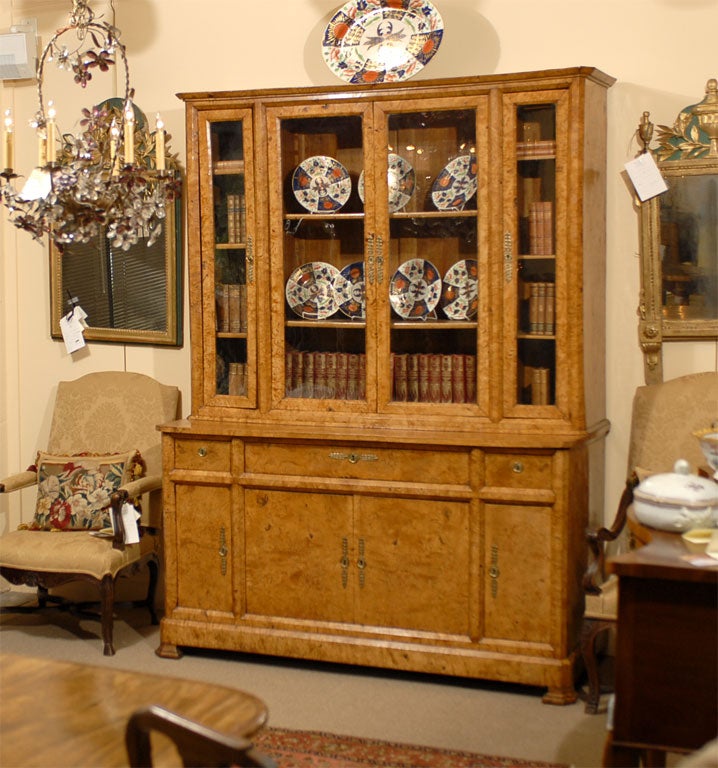 A Charles X Elmwood biblioteque with a secretaire fall-front desk, retaining its original glass panes, and with brass hardware. The display cabinet is segmented into three compartments, resting on a secrataire cupboard with two sliding drawers and