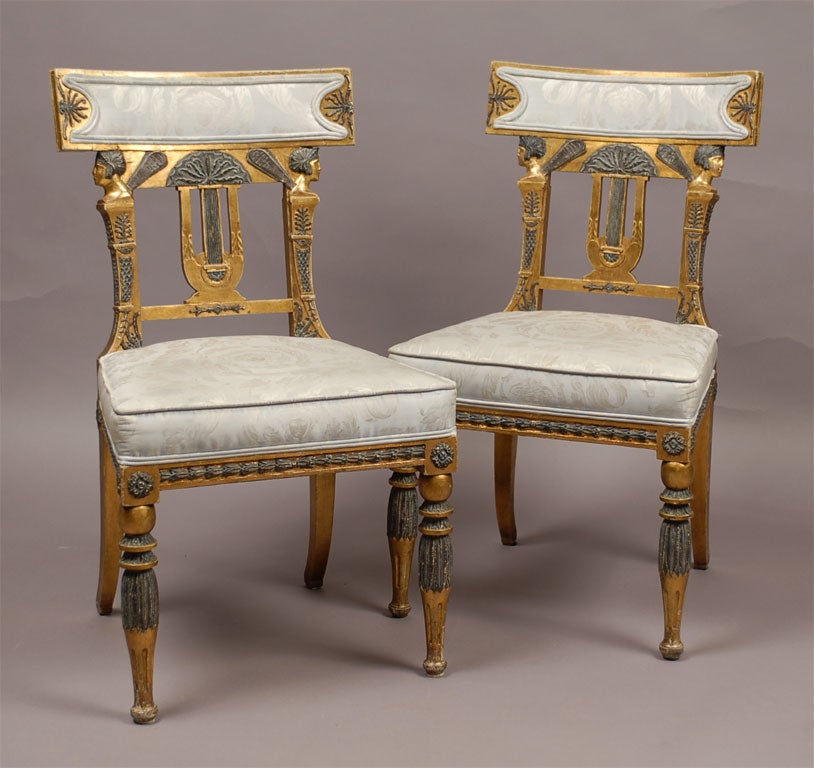 A pair of parcel-gilt and blue-painted side chairs identical to chairs from the Estate of Gianni Versace. The chairs are upholstered in Versace silk fabric, with Gianni Versace's signature Medusa's head centered on the seat and back-rest. The wood