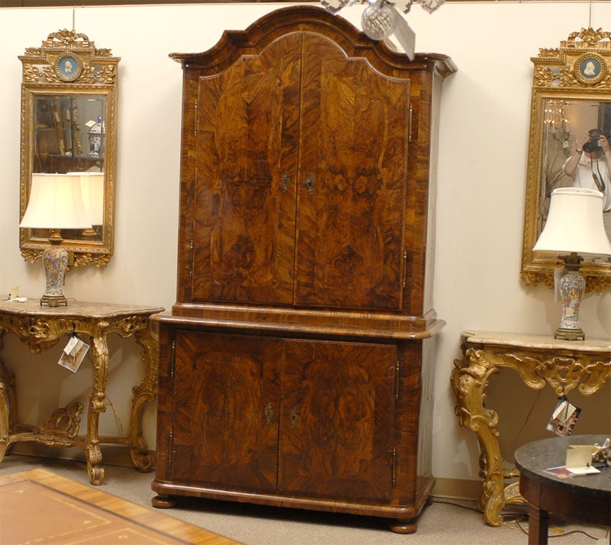 A Buffet deux corps dating from the late 1700s, with a beautiful veneer of burled Walnut covering its streamlined form. The body, capped by an arched molded cornice, is composed of two stacked sections of enclosed cabinet space, fronted by hinged