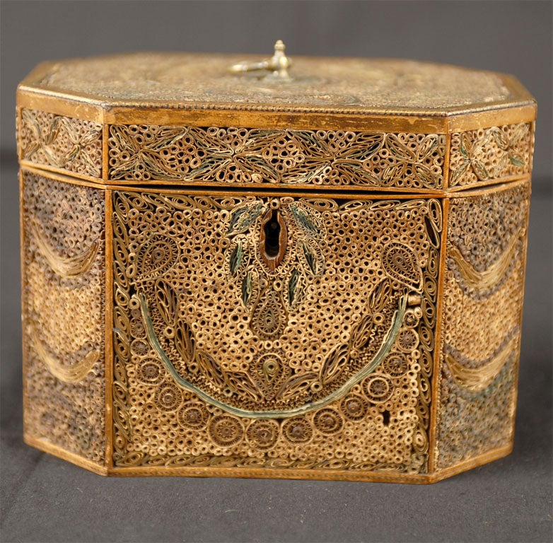 A fine George III period tea caddy, constructed in rolled paper and inlaid wood, with interior metal foil lining and a later interior lid. The exterior is covered with hundreds of rolled paper strips, the designs reflecting Robert Adam's