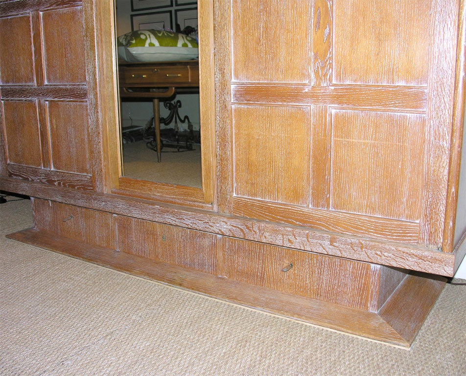 A French 1940’s armoire in cerused oak with three doors, the center one mirrored, three drawers in the base, interior shelving and the original keys.