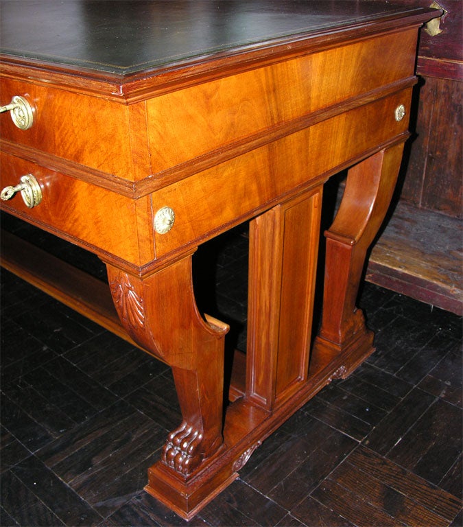 Mid-20th century mahogany writing table, polished molded top above one central drawer flanked by stacked pairs of drawers with brass handles, on carved pedestal supports with foliate decoration, large carved paw feet, joined by flat stretcher.