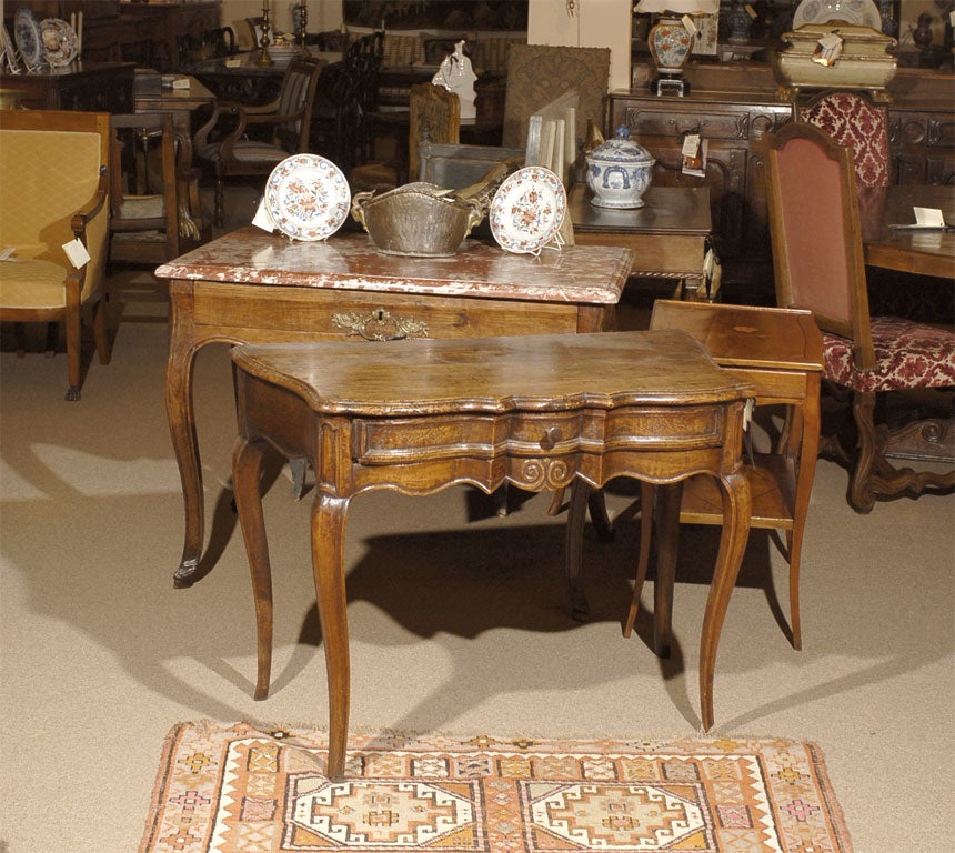 An early Louis XV writing table in elmwood, French in origin, possibly from the Normandy region, and dating from the early 1700s.

The body in a linen-fold shaped form of good depth, and the elm exhibiting a fine acquired patina. The shaped top