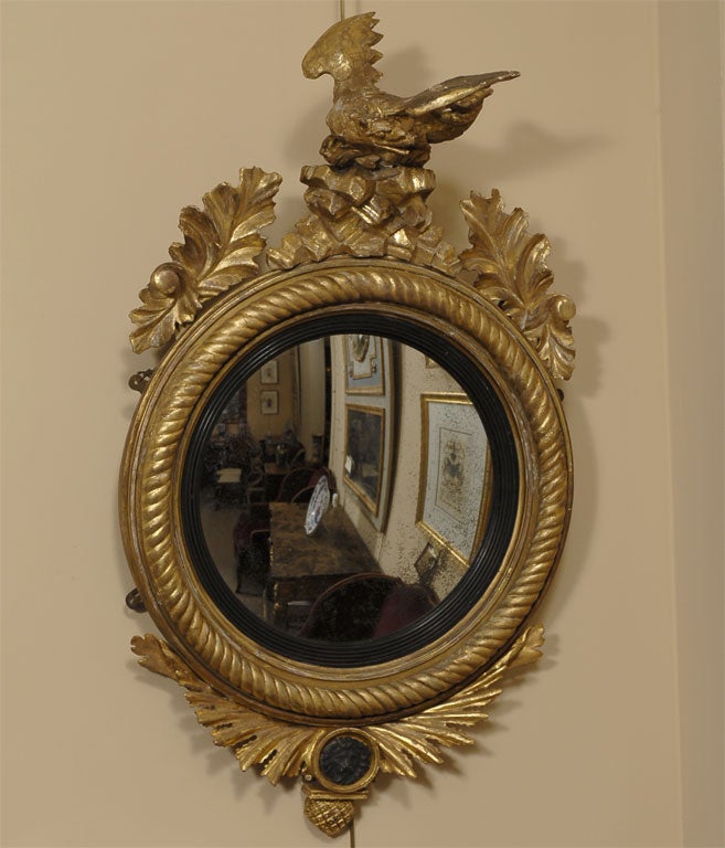 A Regency Period gilt and black-painted convex mirror, also known as a 'bull's-eye' mirror, dating from the early 1800's. 

The original convex mirror plate is reserved by a band of reeded, ebonized wood, then a rope-twist border in gilt.

The