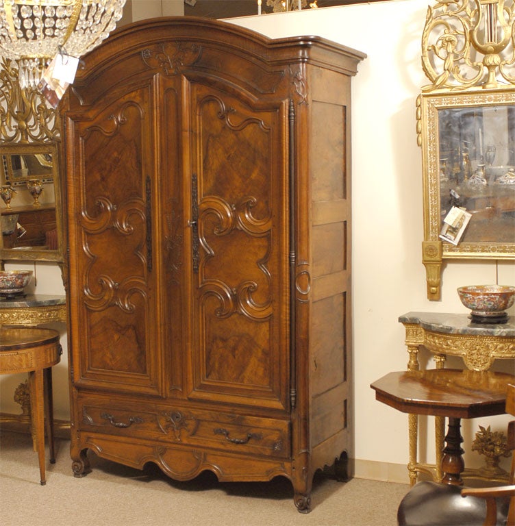 A fine Louis XV period armoire in Walnut, the piece taken from a manor in Bresse, France. The hinged doors with carved scroll borders, reserving panels of burled Walnut. These open to reveal an ample interior space, fitted with the original
