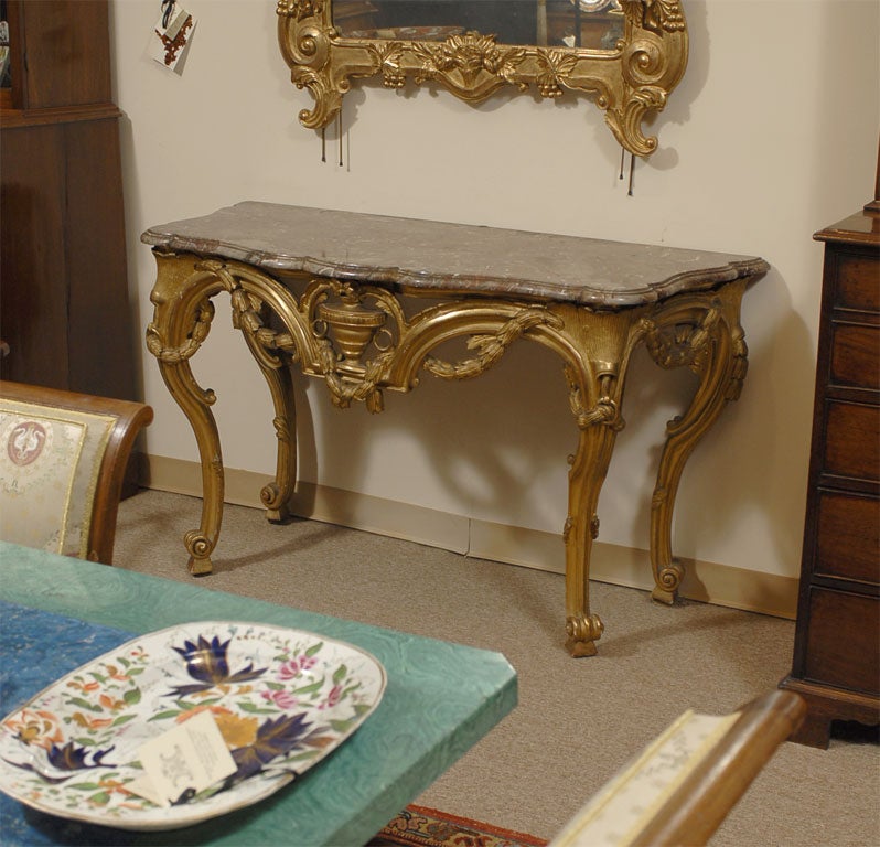 A fine Gilt-wood console of the Louis XV/Louis XVI Transitional design, featuring the original variegated marble slab top, and dating (in both design and construction) from the last half of the 18th century. The gilt-wood frame is constructed in the
