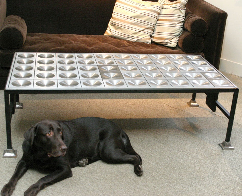 A large and impressive modern style coffee table created from a steel bank vault door. The door set in a painted iron frame with steel feet and the stretcher incorporating matching steel panels as the top.