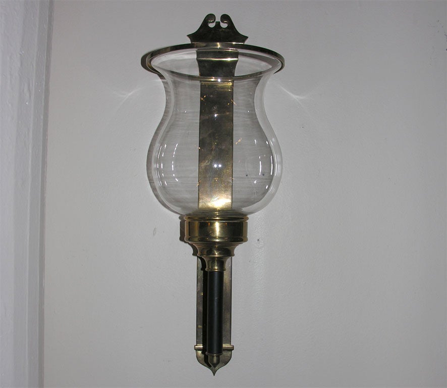 A large pair of brass and glass hurricane wall sconces