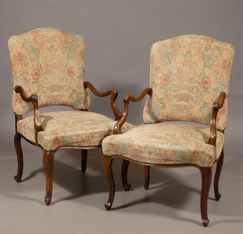 A pair of Fauteuils a le Reine in Walnut, dating from the Regence period and French in Origin. 

The repeated serpentine forms of the chairs are characteristic of the transition into the Louis XV period, and not yet embellished with the carved