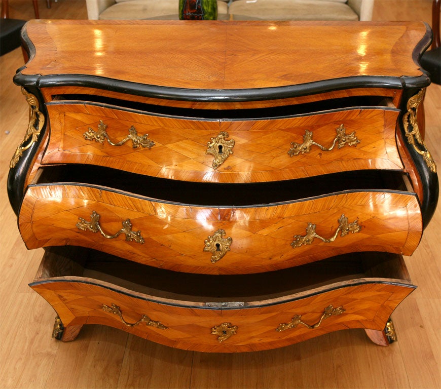 Swedish Louis XV bombe three-drawer chest in birch marquetry with ebonized trim and bronze mounts.