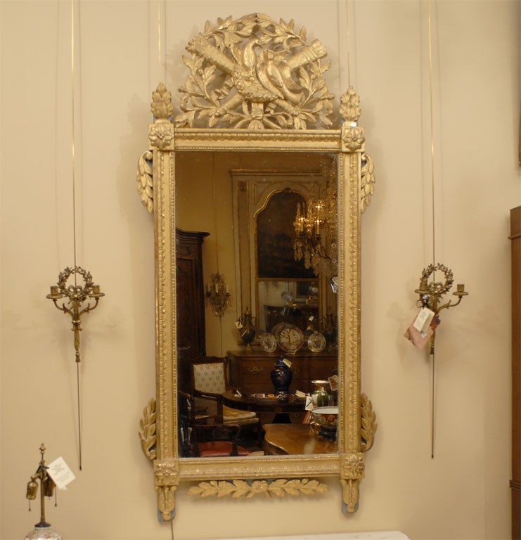 Un beau et grand miroir Louis XVI en bois doré : datant de la fin du XVIIIe siècle, d'origine française.

La plaque de miroir est entourée de bordures néoclassiques et surmontée d'un écusson allégorique de l'