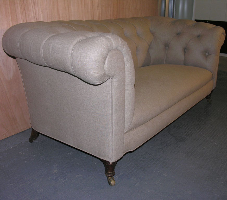 An English 19th century button back chesterfield sofa with rolled arms and back on turned mahogany legs ending in castors.