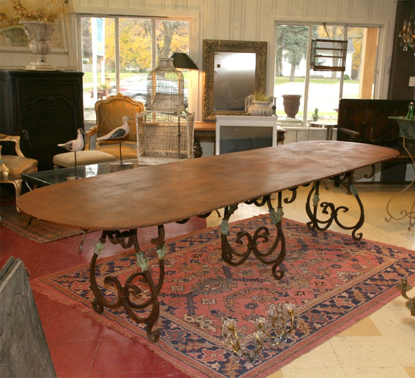 Oval metal dining table with deocorative iron base.