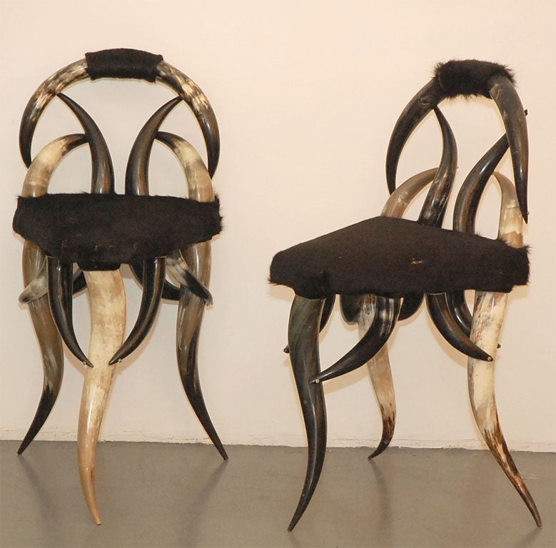 Pair of steer horn chairs with 3 legs and pony hide upholstery.