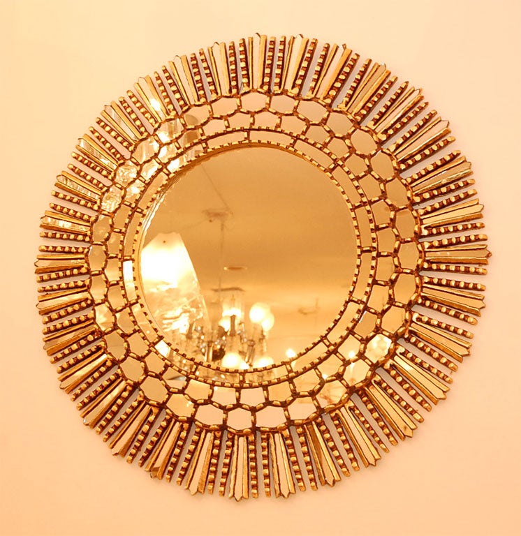 Striking mirror makes a statement with its unique design in the distant style of Line Vautrin. Dozens of small circular mirrors surround the oval center and are framed in a rich gold gilded frame.