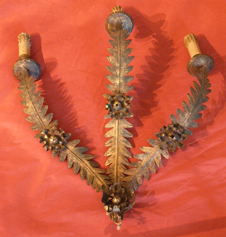 A pair of three arm gilded tole sconces.  The motif of the arms are formed of fern fronds, accented with blossoms. Of Italian origin from the mid-20th century. Wired for the US.