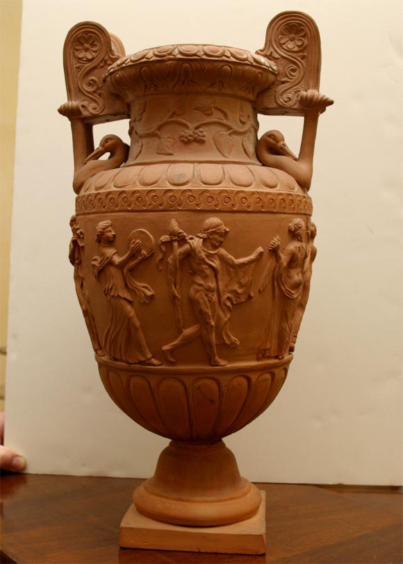 An unglazed classical terra cotta urn with hand applied and finished figures