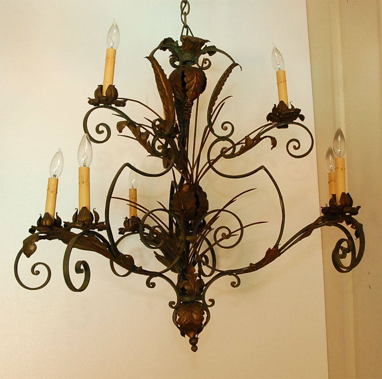 Large, hand wrought and welded 9 light iron chandelier from France.  Original green paint and gilt. Wonderful scrolling quality to the arms, and floral applique decorations.