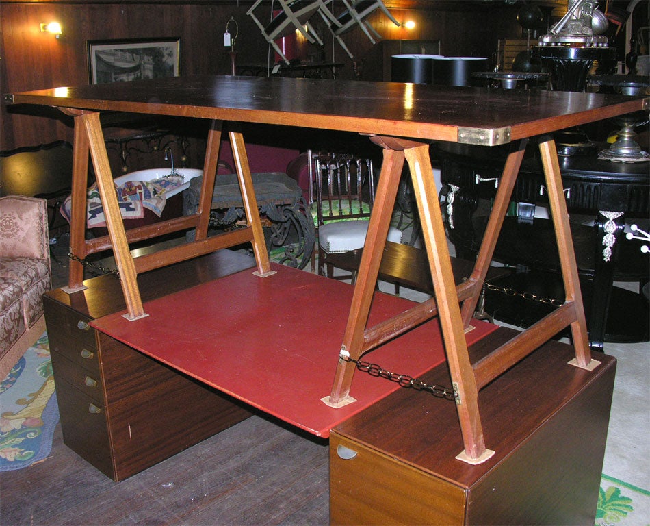 Wood desk with brass trimmed corners and adjustable saw horse legs.