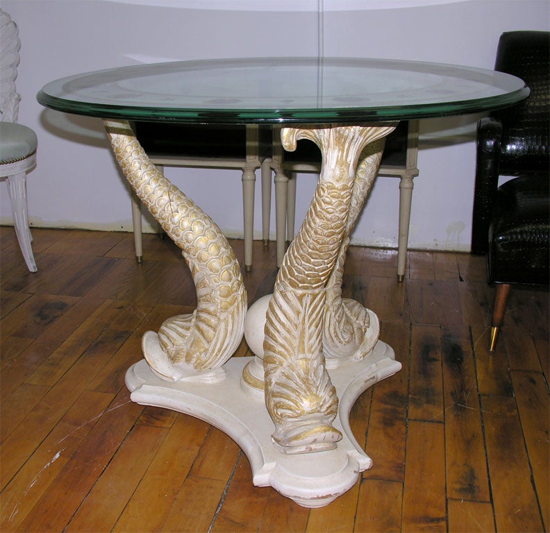 This is a very a lovely pair of small gueridons style round tables raised on three dolphin tails.  The base of is made of carved wood and in the center rests a large wooden pearl. The glass top has a banded eglomise edge with a large shell and  star