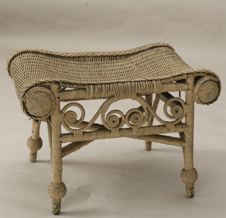 Victorian wicker ottoman in original duo-toned bone painted finish.  Embellished with reed curlicues, intricate medallions and a serpentine rolled design.  This elegantly woven footstool is a fine example from the extensive Corner House Antiques