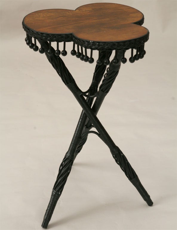 Victorian wicker cloverleaf table painted black with natural stained wood top.Tripod leg design with decorative twisted reeding.  Apron of clover leaf top having multiple stick and ball features. Please view more of the extensive CORNER HOUSE