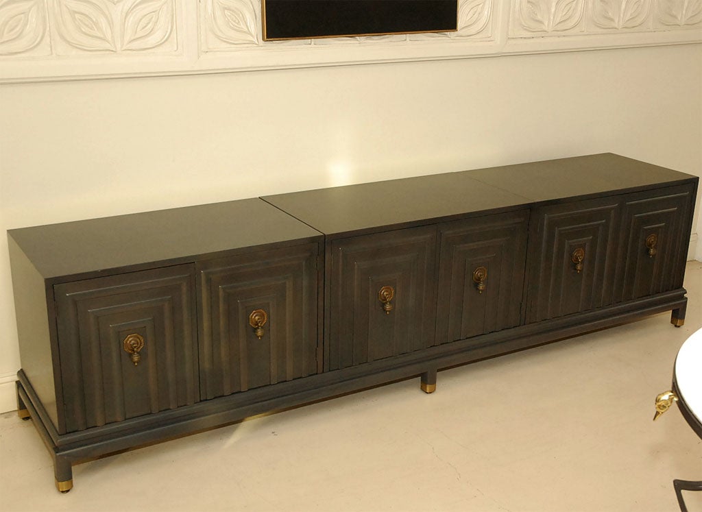 Long, low decorative Johnson Furniture credenza, possibly designed by Bert England, in a grayish brown finish.  Original decorative brass hardware and capped feet.  Interior has lucite shelves.